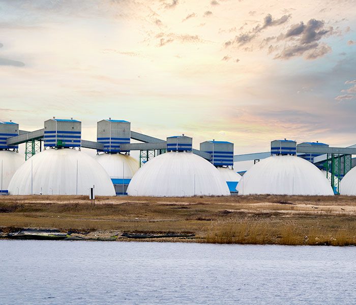 A group oil tanks next to the water.